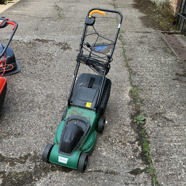 Green Nmlm electric lawnmower in a garden setting.