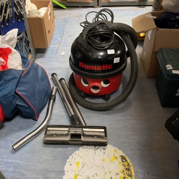 Red Numatic Henry commercial cylinder vacuum cleaner with floor tool.