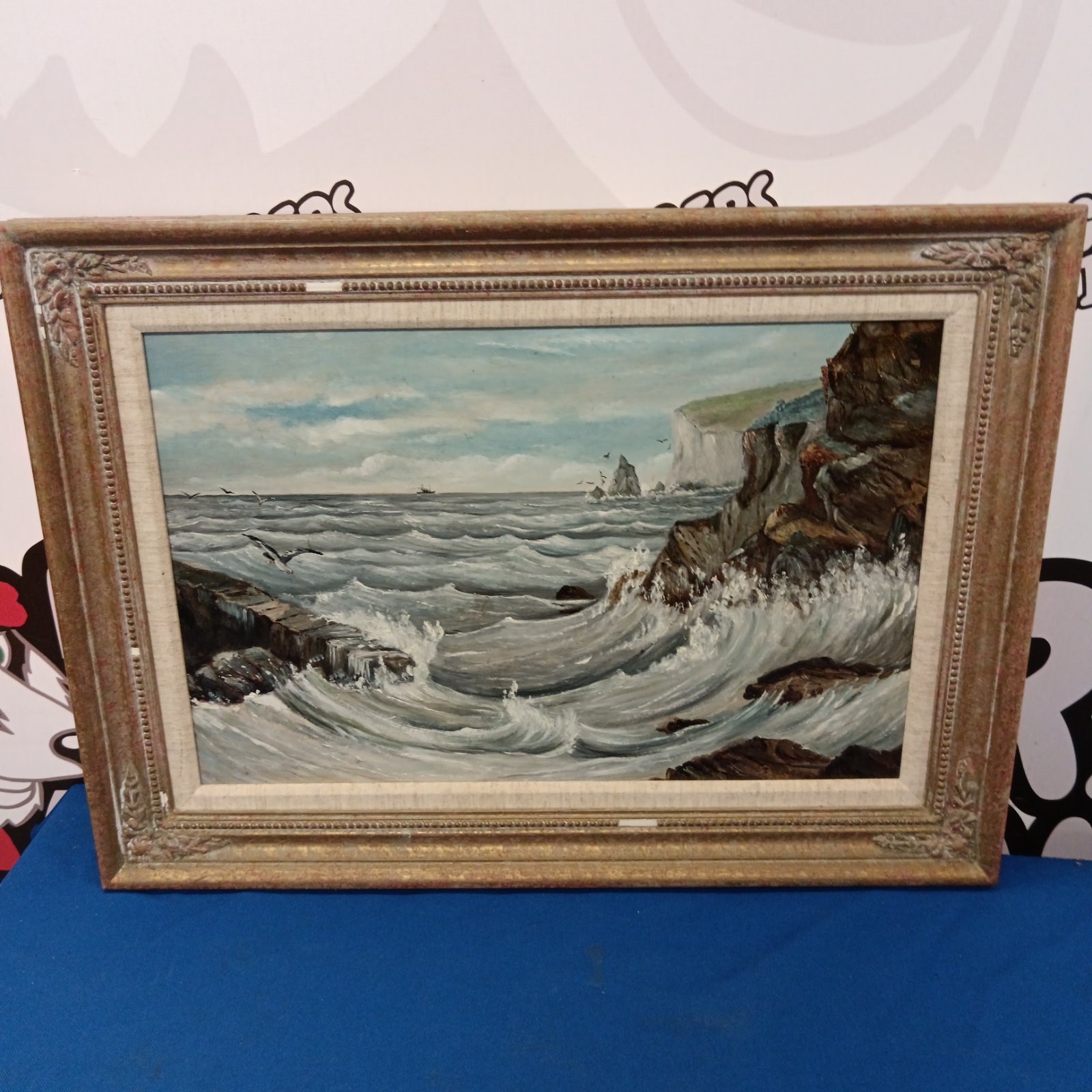 Vintage oil seascape painting of a rugged coastline.