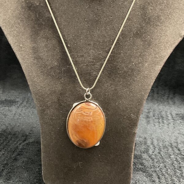 Polished orange stone pendant on a silver necklace.