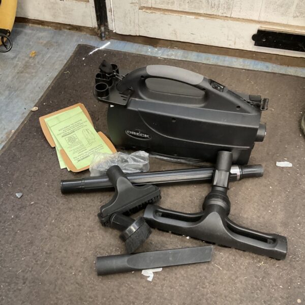Vintage Oreck compact vacuum cleaner with spare bags shown.