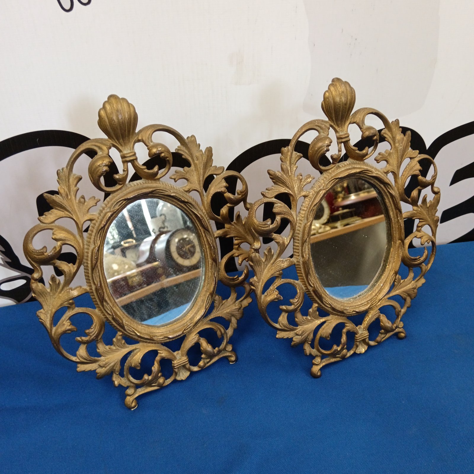 Pair of ornate brass desktop mirrors with detailed frames.