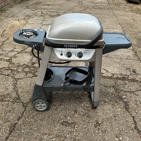 Used Outback gas barbecue grill on a paved surface.