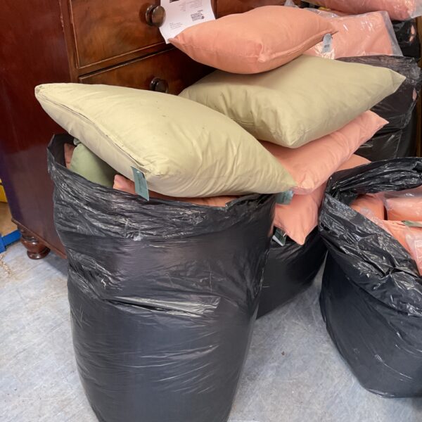 Two bags filled with pink patio furniture cushions.