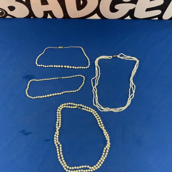 Lot of four vintage pearl necklaces on a dark background.