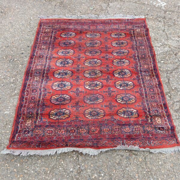 Antique Persian rug with floral design and tassels.