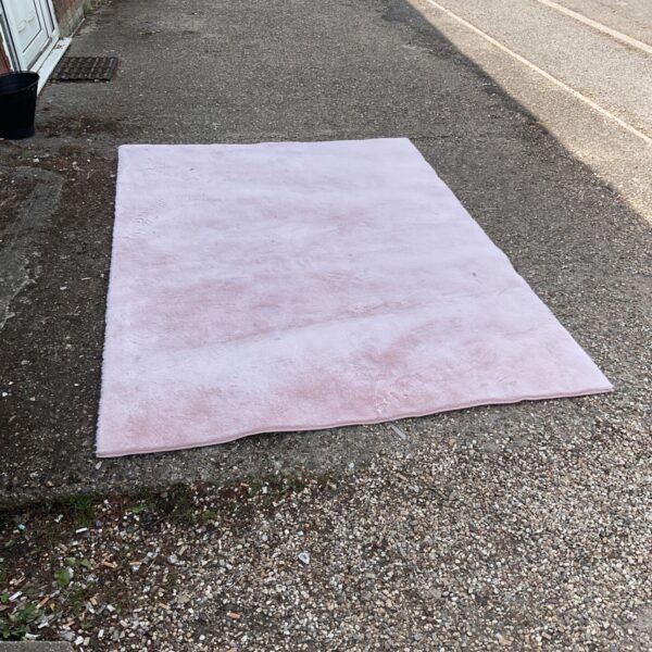 Large pink fluffy rug, approximately 7ft x 5ft, on a driveway.