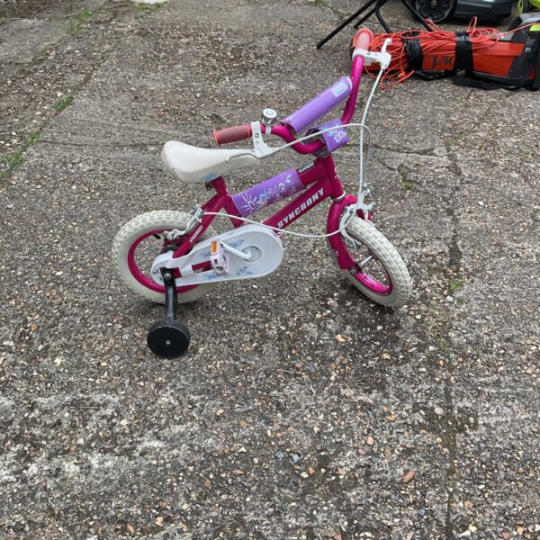 Pink Synchrony child's bicycle with training wheels for young riders.