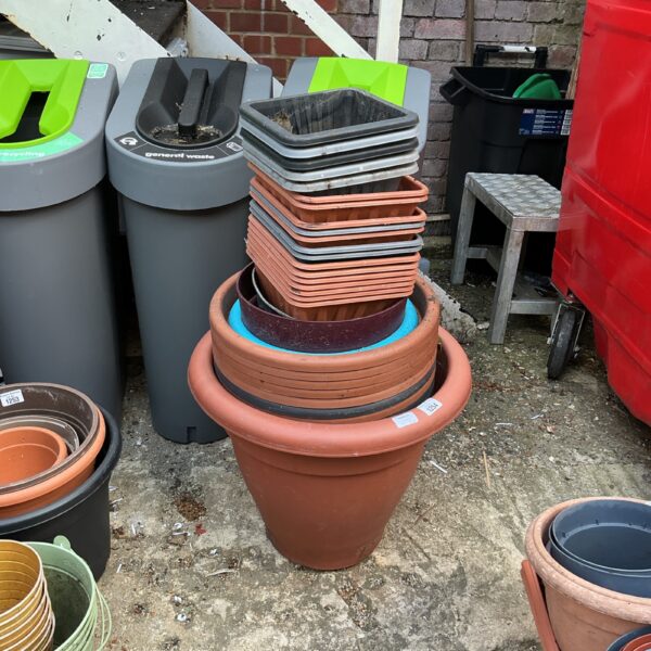 Assorted plastic planters stacked, ideal for garden use.