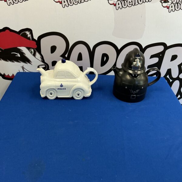 Two vintage police novelty teapots on display.