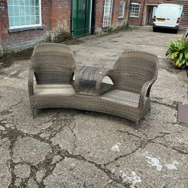 Vintage raffia twin chairs with a central table in a garden setting.