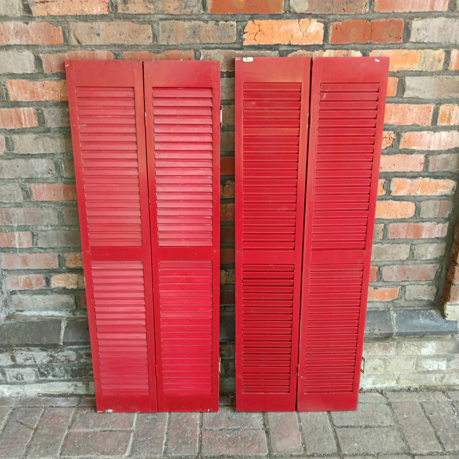 Pair of red wooden window shutters with slatted design.
