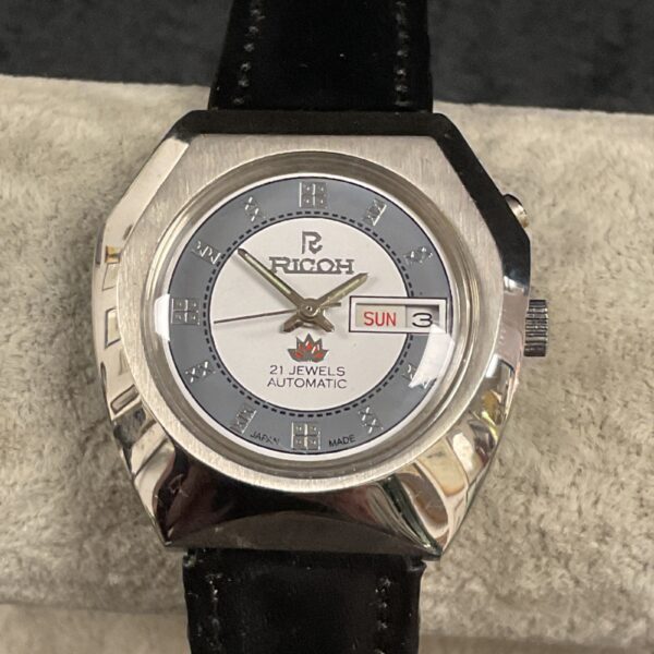 Vintage Ricoh automatic wristwatch with silver dial and leather strap.