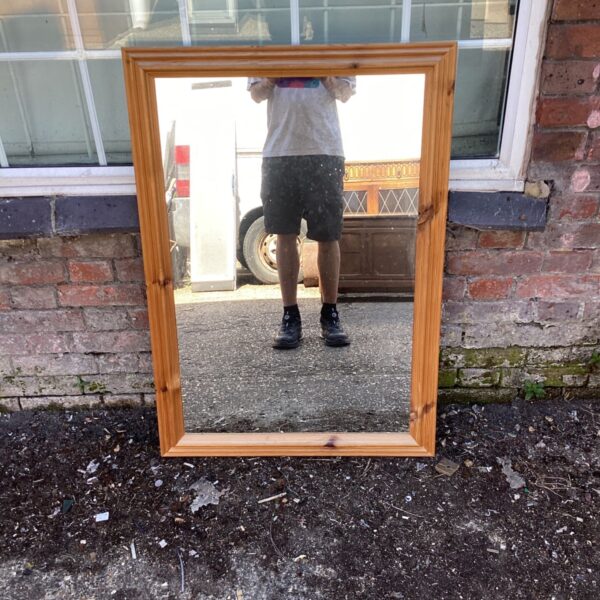 Rustic wooden wall mirror with a thick pine frame.