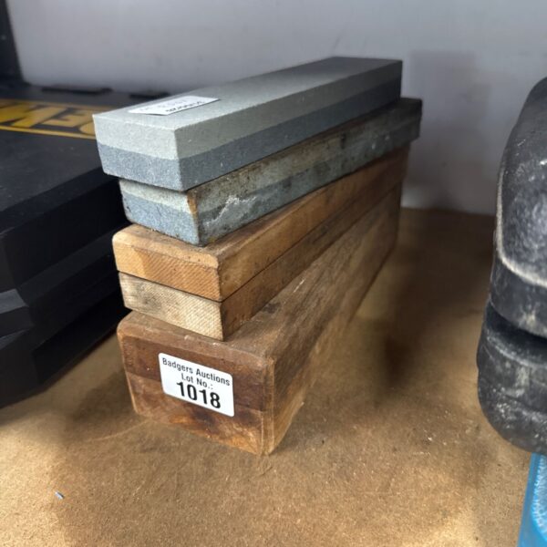 Stack of four grey blade sharpening stones for tool maintenance.