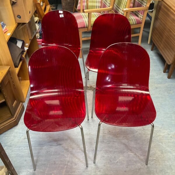 Set of four red Siesta Allegra transparent polycarbonate dining chairs.