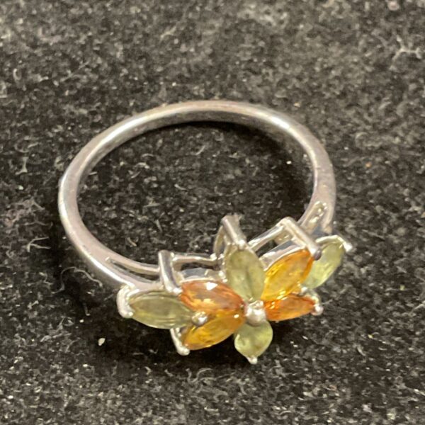 Silver ring with amber and green stones, floral cluster design.