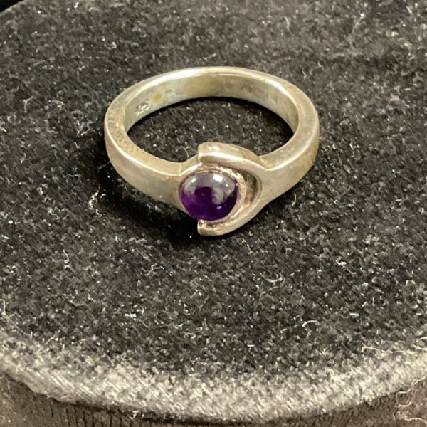 Close-up of a silver ring with a purple amethyst gemstone.