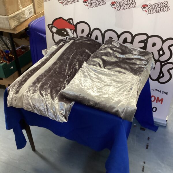 Pair of full length silver curtains displayed on a table.