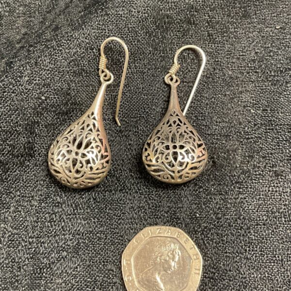 Close-up of silver filigree teardrop earrings with intricate detailing.