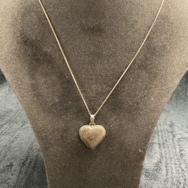 Vintage silver heart locket necklace on a chain.