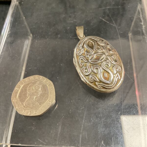 Ornate silver locket pendant with engraved detailing.
