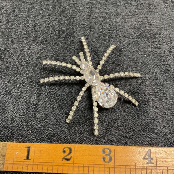 Silver tone spider brooch with clear rhinestones and crystal detail.