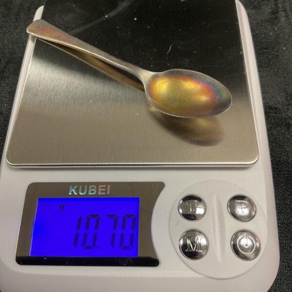 Hallmarked silver teaspoon on a digital scale, weighing 10.7g.
