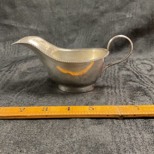 Hallmarked sterling silver cream jug on a dark background.