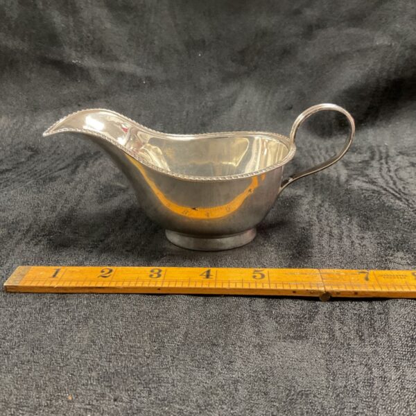 Hallmarked sterling silver cream jug with ruler for scale.