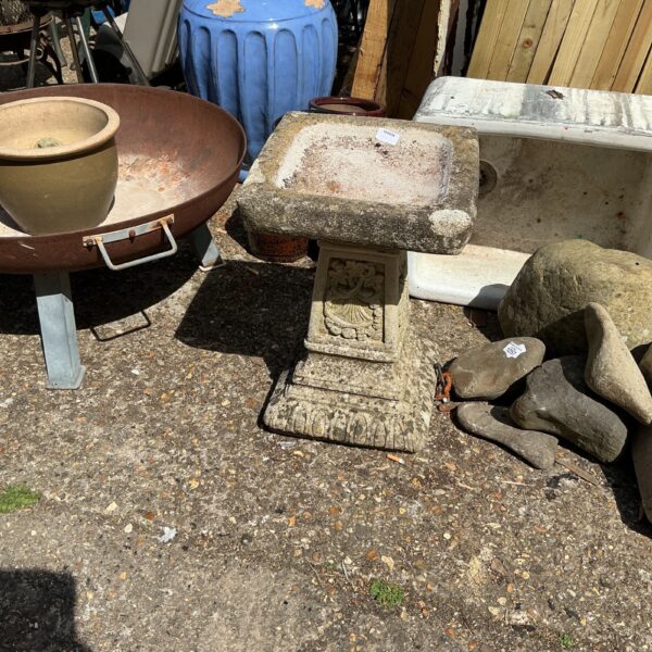 Tiered stone birdbath in a garden setting.