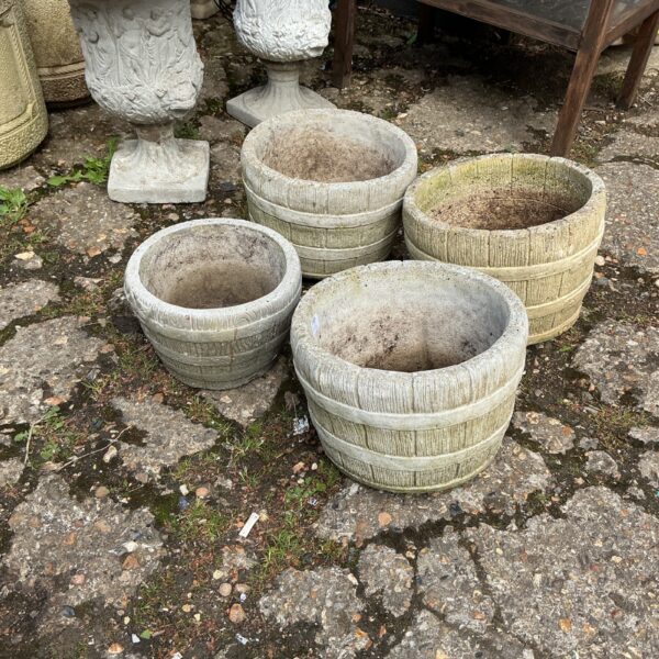 Set of four stone effect garden planters in a garden setting.