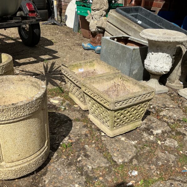 Square stone effect garden planters in a garden setting.