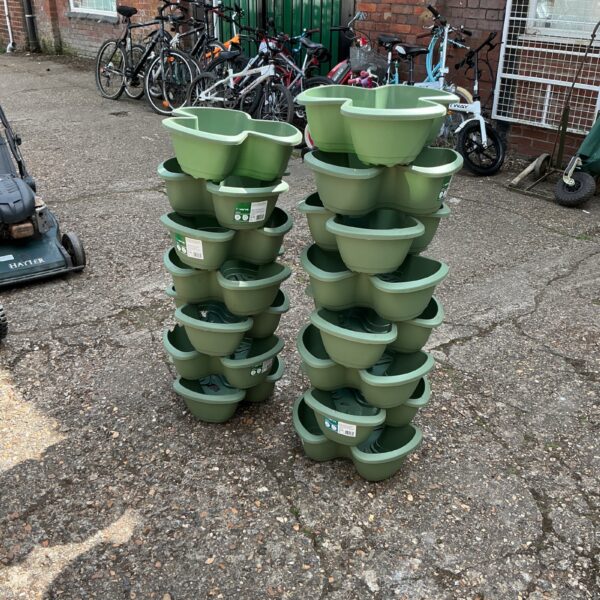 Two Verve strawberry plant towers in a garden setting.