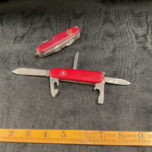 Red handled Victorinox Swiss Army knife and another similar knife.