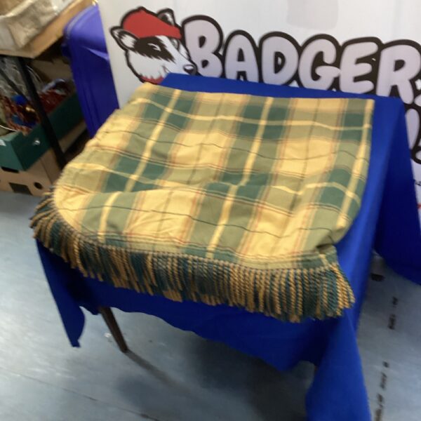 Close-up of a green and gold tartan tablecloth with tassels.