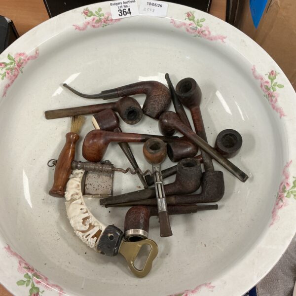 Antique tobacco pipes displayed in a porcelain wash basin.