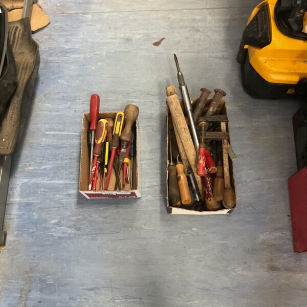Assorted hand tools in boxes, including screwdrivers and hammers.