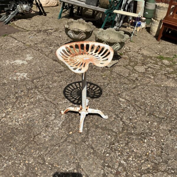 Vintage metal tractor seat stool with rustic patina.