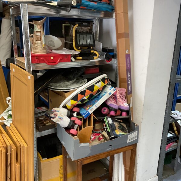 Unclaimed charity lot with assorted items on a metal rack.