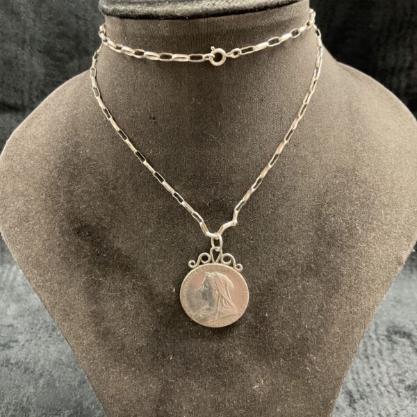 Close-up of vintage Victoria coin pendant necklace on display.