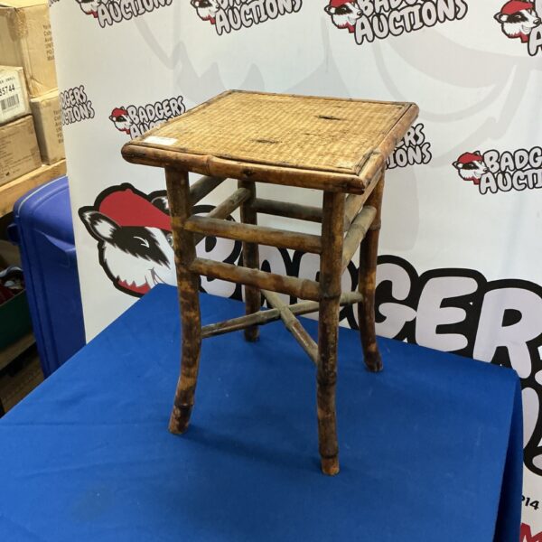Vintage bamboo plant stand with woven detail, ideal for displaying flowers.