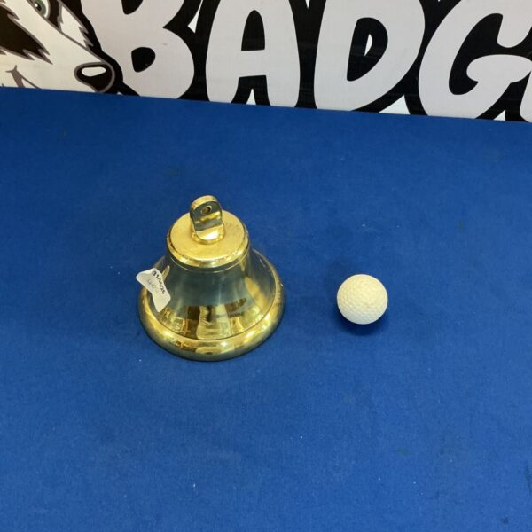 Vintage brass bell on a blue surface with a white background.