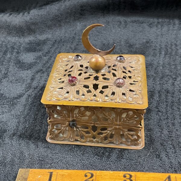 Intricate vintage brass filigree box with crescent moon detail.