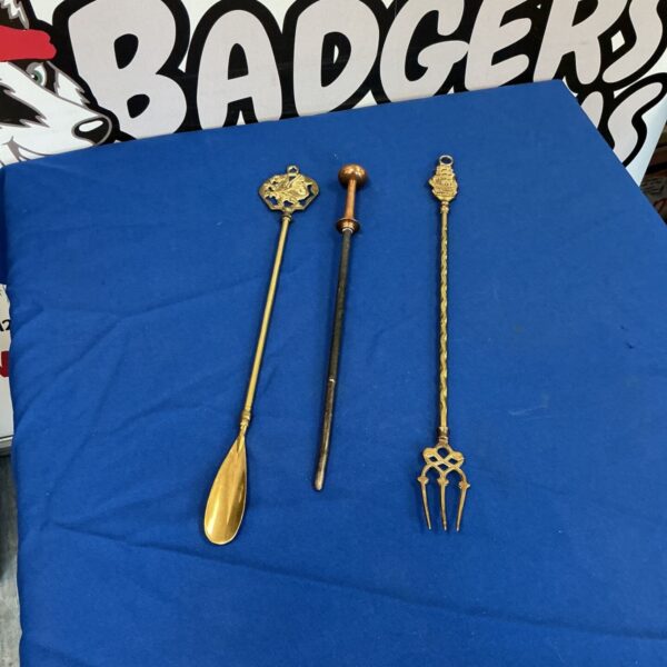 Vintage brass fire tools including poker, shovel, and tongs.