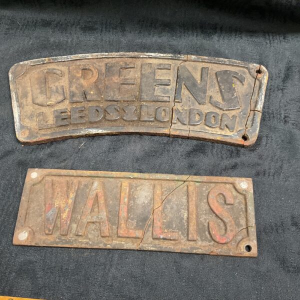 Vintage cast iron plaque reading "GREENS LEEDS LONDON" with rust.