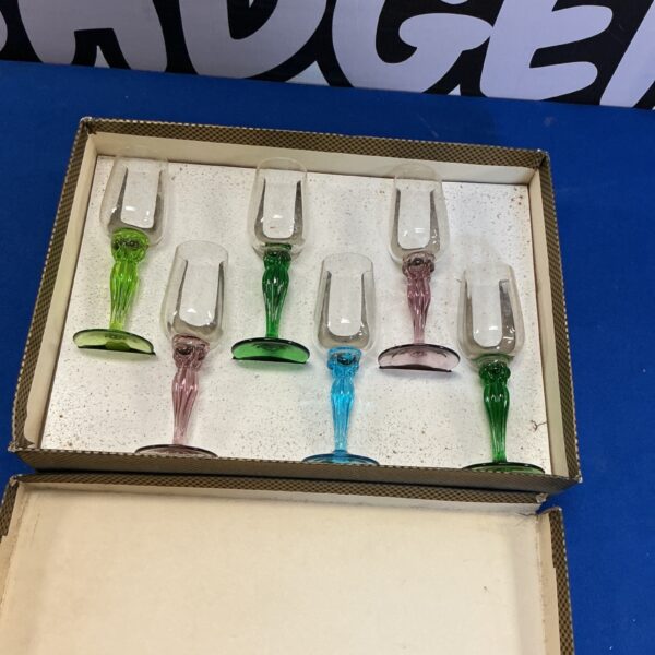 Set of four vintage coloured wine glasses on a dark surface.