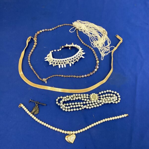 Vintage costume jewelry necklaces and a horse brooch on display.