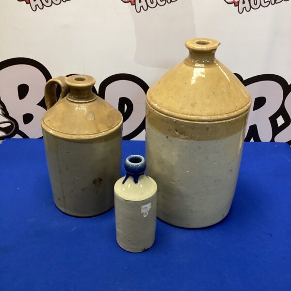 Three vintage earthenware flagons displayed on a patterned background.