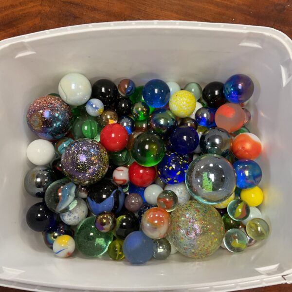 Colorful vintage glass marbles in a tub, collectible toy marbles.
